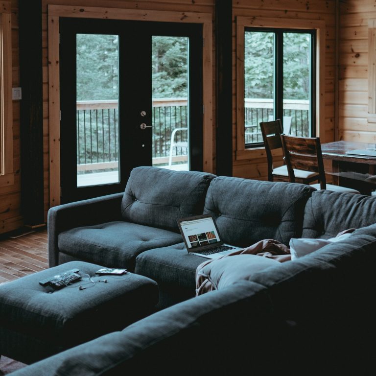 Gemütliches Wohnzimmer mit Couch, Kaffeetisch und großen Fenstern zum Außenbereich.